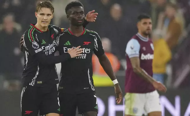 Arsenal's Martin Odegaard, left, celebrates with Arsenal's Bukayo Saka after scoring his side's third goal during the English Premier League soccer match between West Ham and Arsenal at the London Stadium in London, Saturday, Nov. 30, 2024. (AP Photo/Dave Shopland)