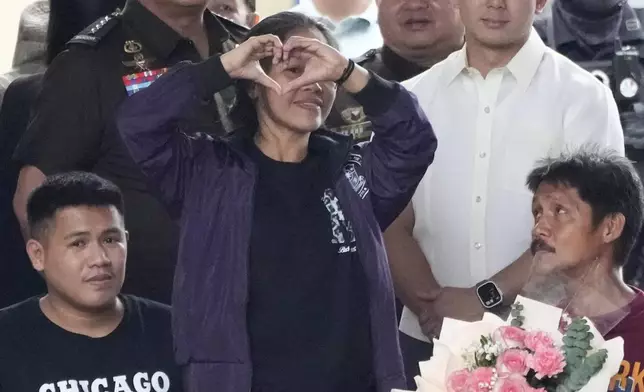 CORRECTS TO FAMILY INSTEAD OF SON AND HUSBAND - Mary Jane Veloso, center, a Filipino woman who spent almost 15 years in an Indonesian prison for drug trafficking and was nearly executed by firing squad in 2015, shows a heart sign as she is reunited with her family as she arrives at the Correctional Institution for Women in Mandaluyong, Philippines Wednesday, Dec. 18, 2024. (AP Photo/Aaron Favila)
