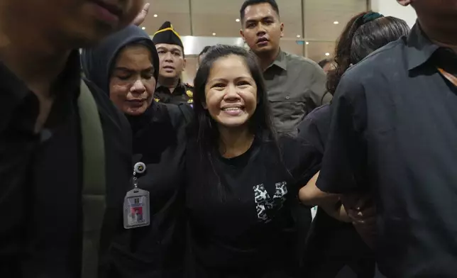 Mary Jane Veloso, center, a Filipina who was on death row in Indonesia and was nearly executed by firing squad in 2015, smiles as she arrives at Soekarno-Hatta International Airport for her repatriation to the Philippines, in Tangerang, Indonesia, Tuesday, Dec. 17, 2024. (AP Photo/Tatan Syuflana)