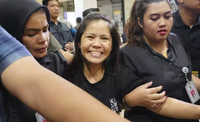 Mary Jane Veloso, center, a Filipina who was on death row in Indonesia and was nearly executed by firing squad in 2015, smiles as she arrives at Soekarno-Hatta International Airport for her repatriation to the Philippines, in Tangerang, Indonesia, Tuesday, Dec. 17, 2024. (AP Photo/Tatan Syuflana)