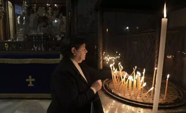 A worshipper lights a candle in the Church of the Nativity, where Christians believe Jesus Christ was born, ahead of Christmas in the West Bank city of Bethlehem, Tuesday, Dec. 17, 2024. (AP Photo/Mahmoud Illean)