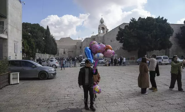 A boy sells balloons outside the Church of the Nativity, where Christians believe Jesus Christ was born, ahead of Christmas in the West Bank city of Bethlehem, Saturday Dec. 21, 2024. (AP Photo/Mahmoud Illean)