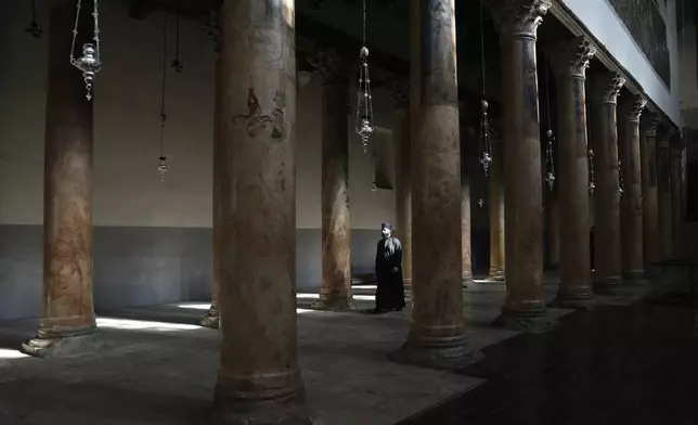 A priest walks in the Church of the Nativity, where Christians believe Jesus Christ was born, ahead of Christmas in the West Bank city of Bethlehem, Tuesday, Dec. 17, 2024. (AP Photo/Mahmoud Illean)