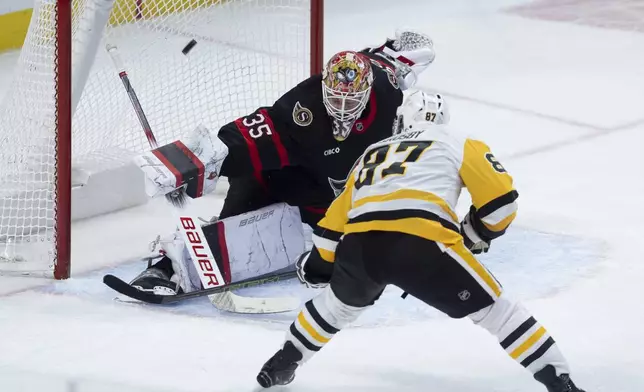 Ottawa Senators goaltender Linus Ullmark (35) deflects a shot by Pittsburgh Penguins center Sidney Crosby, foreground, over the net during second-period NHL hockey game action in Ottawa, Ontario, Saturday, Dec. 14, 2024. (Adrian Wyld/The Canadian Press via AP)