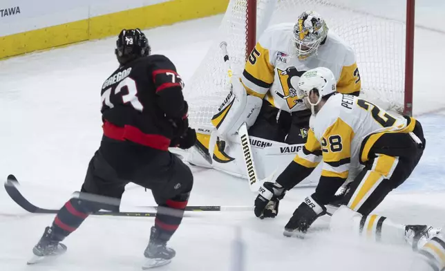 Pittsburgh Penguins goaltender Tristan Jarry (35) makes a save against Ottawa Senators left wing Noah Gregor (73) as Gregor is pressured by defenseman Marcus Pettersson (28) during first-period NHL hockey game action in Ottawa, Ontario, Saturday, Dec. 14, 2024. (Adrian Wyld/The Canadian Press via AP)