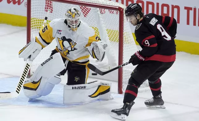 Ottawa Senators center Josh Norris (9) tries to tip a shot past Pittsburgh Penguins goaltender Tristan Jarry, left, during second-period NHL hockey game action in Ottawa, Ontario, Saturday, Dec. 14, 2024. (Adrian Wyld/The Canadian Press via AP)