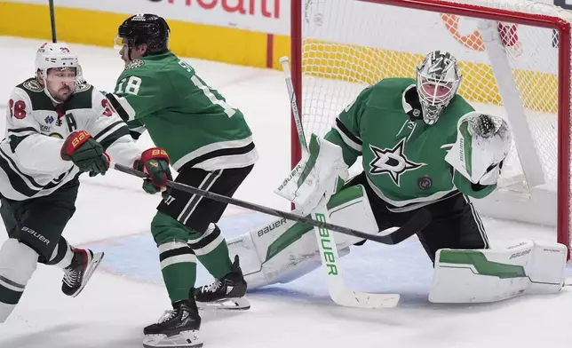 Dallas Stars goaltender Jake Oettinger (29) and center Sam Steel (18) defend the goal against Minnesota Wild right wing Ryan Hartman (38) during the third period of an NHL hockey game Friday, Dec. 27, 2024, in Dallas. (AP Photo/LM Otero)