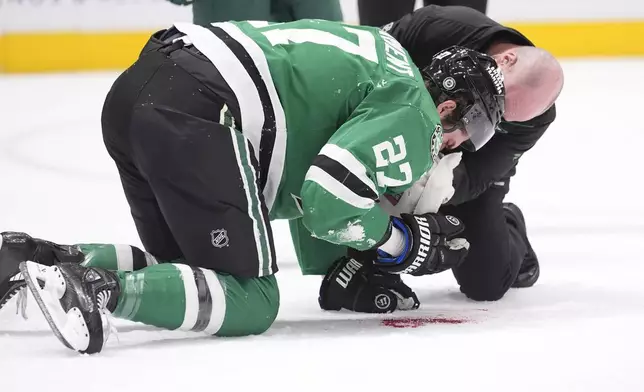 Dallas Stars left wing Mason Marchment (27) is tended to after he was hit by the puck during the first period of an NHL hockey game against the Minnesota Wild, Friday, Dec. 27, 2024, in Dallas. (AP Photo/LM Otero)
