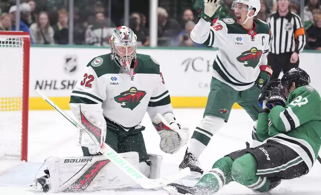 Dallas Stars left wing Mason Marchment (27) falls to ice as Minnesota Wild defenseman Jared Spurgeon (46) calls for an end to play after Marchment was hit by a puck in front of Wild goaltender Filip Gustavsson (32) during the first period of an NHL hockey game Friday, Dec. 27, 2024, in Dallas. (AP Photo/LM Otero)