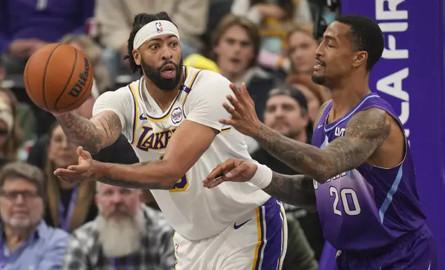 Los Angeles Lakers forward Anthony Davis, left, passes the ball around Utah Jazz forward John Collins (20) during the first half of an NBA basketball game Sunday, Dec. 1, 2024, in Salt Lake City. (AP Photo/Bethany Baker)