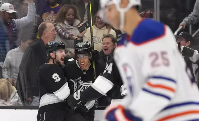 Los Angeles Kings right wing Quinton Byfield, second from left, celebrates his game-winning goal with right wing Adrian Kempe, left, as Edmonton Oilers defenseman Darnell Nurse skates off during the overtime period of an NHL hockey game, Saturday, Dec. 28, 2024, in Los Angeles. (AP Photo/Mark J. Terrill)