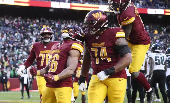 Washington Commanders running back Jeremy McNichols (26) celebrating his two-point conversion against the Philadelphia Eagles with his teammates during the second half of an NFL football game, Sunday, Dec. 22, 2024, in Landover, Md. (AP Photo/Nick Wass)