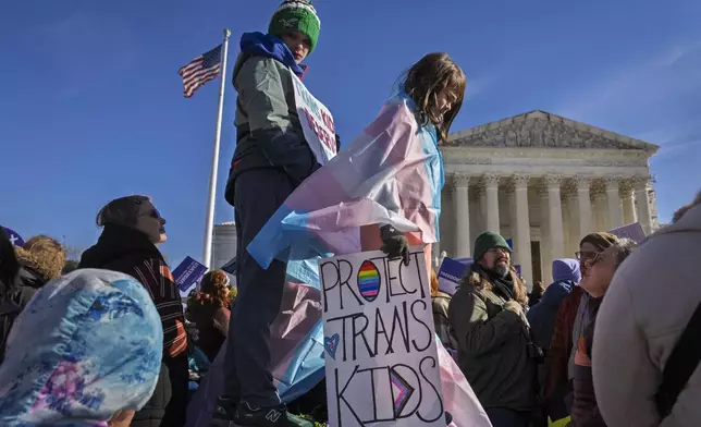 Nate, 14, left, and Bird, 9, right, whose parents asked not to use their last names, hold signs and transgender pride flags as supporters of transgender rights rally by the Supreme Court, Wednesday, Dec. 4, 2024, in Washington, while arguments are underway in a case regarding a Tennessee law banning gender-affirming medical care for transgender youth. (AP Photo/Jacquelyn Martin)