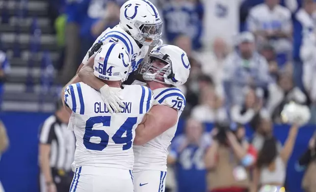 Indianapolis Colts running back Jonathan Taylor, top celebrates his touchdown with guard Mark Glowinski (64) and offensive tackle Bernhard Raimann (79) during the second half of an NFL football game against the Tennessee Titans, Sunday, Dec. 22, 2024, in Indianapolis. (AP Photo/Michael Conroy)