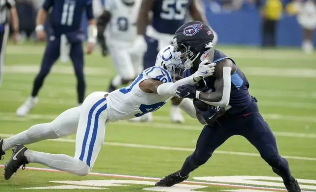 Tennessee Titans running back Tyjae Spears, right, is tackled by Indianapolis Colts cornerback Jaylon Jones, left, during the second half of an NFL football game Sunday, Dec. 22, 2024, in Indianapolis. (AP Photo/Darron Cummings)