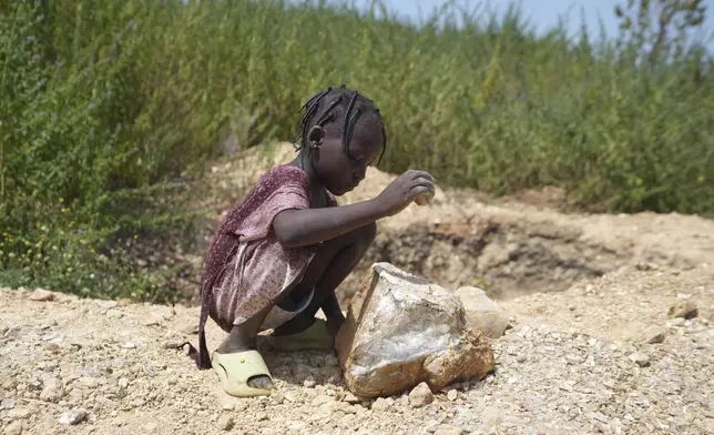 Juliet Samaniya, 6, chips at a rock with a stone tool at an illegal lithium mining site in Paseli, Nigeria, Tuesday, Nov 5, 2024. (AP Photo/Sunday Alamba)