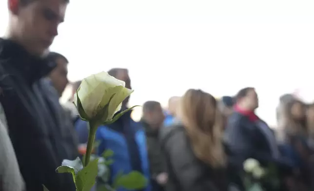 Students hold white flowers in front of the court building during a verdict in trial of parents of a boy who killed 9 students and security guard in school shooting in 2023, in Belgrade, Serbia, Monday, Dec. 30, 2024. (AP Photo/Darko Vojinovic)