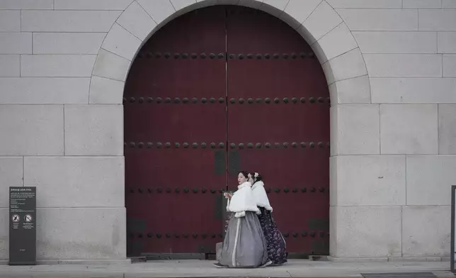 Visitors wearing South Korean traditional costume "Hanbok" was in front of the Gwanghwamun, the main gate of the 14th-century Gyeongbok Palace, one of South Korea's well known landmarks, in Seoul, South Korea, Wednesday, Dec. 4, 2024. (AP Photo/Lee Jin-man)