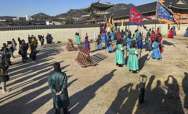 Tourists watch the rehearsal for the royal guard changing ceremony at the Gyeongbokgung Palace, in Seoul, Wednesday, Dec. 4, 2024. (AP Photo/ Jennifer McDermott)