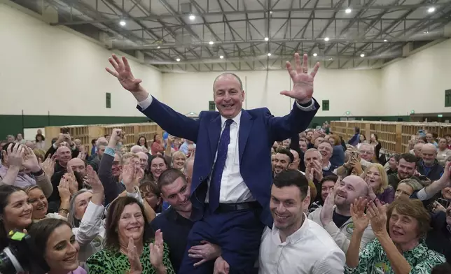 Fianna Fail leader Micheal Martin is hoisted up by his sons Cillian and Micheal Aodh, after he was deemed elected in the Cork South Central constituency at the election count centre at Nemo Rangers GAA Club in Cork, after the General Election, Saturday Nov. 30, 2024. (Jacob King/PA via AP)