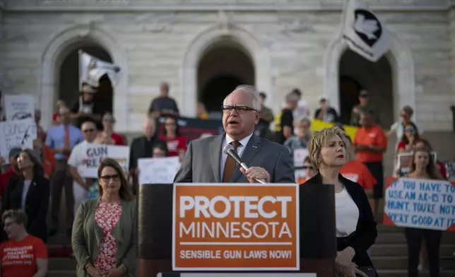 FILE - Gov. Tim Walz speaks before a crowd gathered for a rally on the steps of the state Capitol in St. Paul, Minn., Wednesday evening, Aug. 7, 2019. Lt. Gov. Peggy Flanagan, center left, and his wife Gwen Walz, center right, stand by him. (Jeff Wheeler/Star Tribune via AP, File)