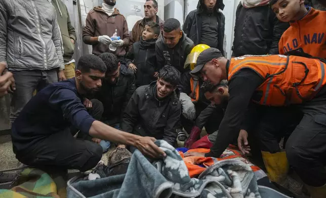 Palestinians mourn over the bodies of civil defense workers victims of an Israeli army strike in the Nuseirat camp, at the Al-Aqsa Martyrs hospital in Deir al-Balah, central Gaza Strip, Sunday Dec.16, 2024. Four cicivil defence workers were killed according to Palestinian civil defense and health ministry.(AP Photo/Abdel Kareem Hana)