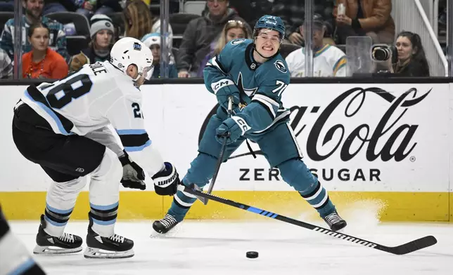 San Jose Sharks center Macklin Celebrini (71) crosses the puck against Utah Hockey Club defenseman Ian Cole (28) during the first period of an NHL hockey game Saturday, Dec. 14, 2024, in San Jose, Calif. (AP Photo/Eakin Howard)