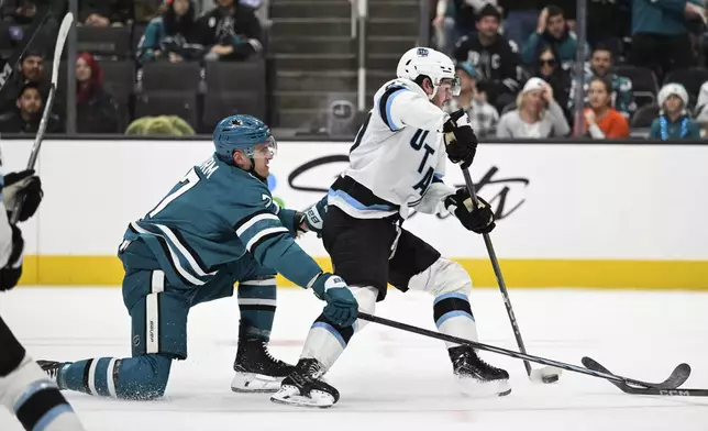 Utah Hockey Club center Barrett Hayton (27) control the puck against San Jose Sharks center Nico Sturm (7) during the second period of an NHL hockey game Saturday, Dec. 14, 2024, in San Jose, Calif. (AP Photo/Eakin Howard)