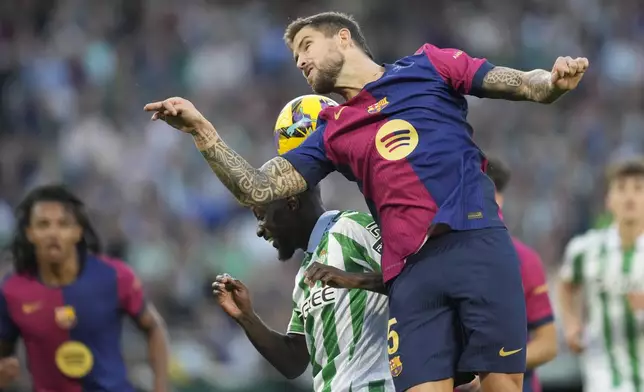 Barcelona's Inigo Martinez, right, challenges for the ball with Betis' Youssouf Sabaly during a Spanish La Liga soccer match between Betis and Barcelona at the Benito Villamarin stadium in Seville, Spain, Saturday, Dec. 7, 2024. (AP Photo/Jose Breton)