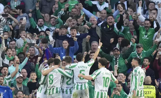 Real Betis players celebrate after Betis' Giovani Lo Celso scored his side's opening goal during a Spanish La Liga soccer match between Betis and Barcelona at the Benito Villamarin stadium in Seville, Spain, Saturday, Dec. 7, 2024. (AP Photo/Jose Breton)