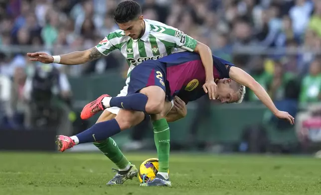 Barcelona's Dani Olmo, right, challenges for the ball with Betis' Marc Bartra during a Spanish La Liga soccer match between Betis and Barcelona at the Benito Villamarin stadium in Seville, Spain, Saturday, Dec. 7, 2024. (AP Photo/Jose Breton)