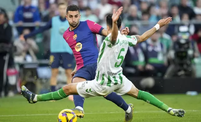 Barcelona's Ferran Torres kicks the ball ahead of Betis' Marc Bartra during a Spanish La Liga soccer match between Betis and Barcelona at the Benito Villamarin stadium in Seville, Spain, Saturday, Dec. 7, 2024. (AP Photo/Jose Breton)