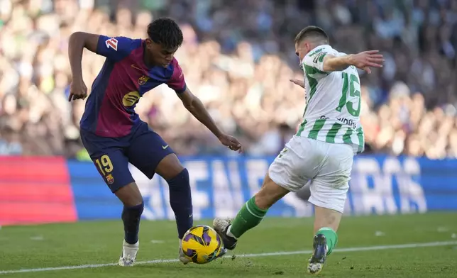 Barcelona's Lamine Yamal, left, challenges for the ball with Betis' Romain Perraud during a Spanish La Liga soccer match between Betis and Barcelona at the Benito Villamarin stadium in Seville, Spain, Saturday, Dec. 7, 2024. (AP Photo/Jose Breton)