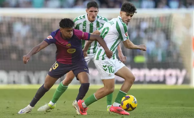 Barcelona's Lamine Yamal, left, challenges for the ball with Betis' Abde Ezzalzouli during a Spanish La Liga soccer match between Betis and Barcelona at the Benito Villamarin stadium in Seville, Spain, Saturday, Dec. 7, 2024. (AP Photo/Jose Breton)