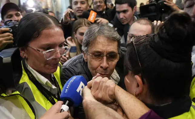 Fabio Ochoa, center, a former member of Cartel of Medellin, kisses a relative's hand upon his arrival at El Dorado airport, after being deported from the United States, in Bogota, Colombia, Monday, Dec. 23, 2024. (AP Photo/Fernando Vergara)