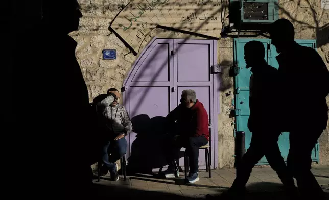 Men gather outside closed businesses next to the Church of the Nativity, traditionally believed to be the birthplace of Jesus, on Christmas Eve, in the West Bank city of Bethlehem, Tuesday, Dec. 24, 2024. (AP Photo/Matias Delacroix)