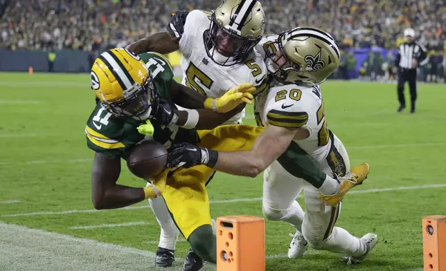 Green Bay Packers wide receiver Jayden Reed (11) is pushed out of bounds near the goal line by New Orleans Saints cornerback Will Harris (5) and linebacker Pete Werner (20) during the first half of an NFL football game, Monday, Dec. 23, 2024, in Green Bay, Wis. (AP Photo/Matt Ludtke)