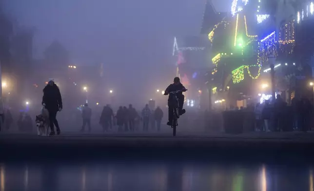 A person rides their bike on Front Street in the fog on Tuesday, Nov. 26, 2024, in Leavenworth, Wash. (AP Photo/Jenny Kane)