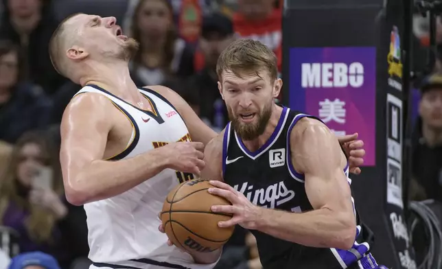 Denver Nuggets center Nikola Jokic, left, and Sacramento Kings forward Domantas Sabonis, right, battle for the ball during the first half of an NBA basketball game in Sacramento, Calif., Monday, Dec. 16, 2024. (AP Photo/Randall Benton)