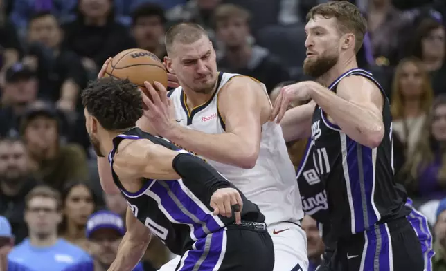 Denver Nuggets center Nikola Jokic, center, is guarded by Sacramento Kings forward Domantas Sabonis (11) during the second half of an NBA basketball game in Sacramento, Calif., Monday, Dec. 16, 2024. The Nuggets won 130-129. (AP Photo/Randall Benton)