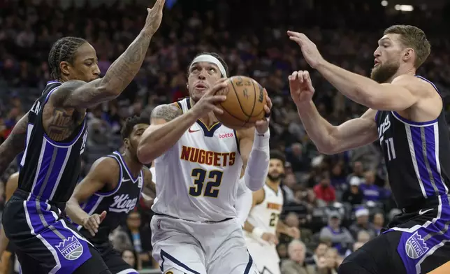 Denver Nuggets forward Aaron Gordon (32) is guarded by Sacramento Kings forward DeMar DeRozan, left, and Domantas Sabonis during the first half of an NBA basketball game in Sacramento, Calif., Monday, Dec. 16, 2024. (AP Photo/Randall Benton)
