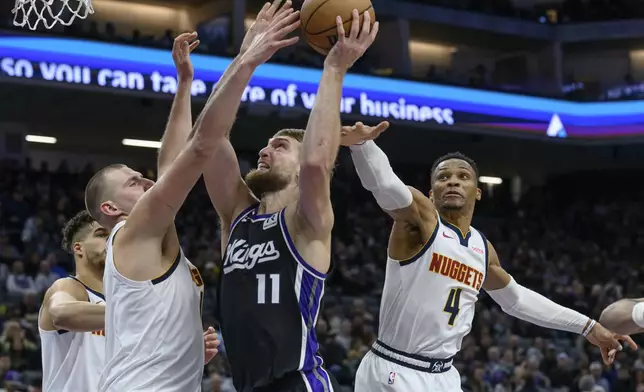 Sacramento Kings forward Domantas Sabonis (11) shoots over Denver Nuggets center Nikola Jokic, lefty, and Russell Westbrook during the second half of an NBA basketball game in Sacramento, Calif., Monday, Dec. 16, 2024. The Nuggets won 130-129. (AP Photo/Randall Benton)