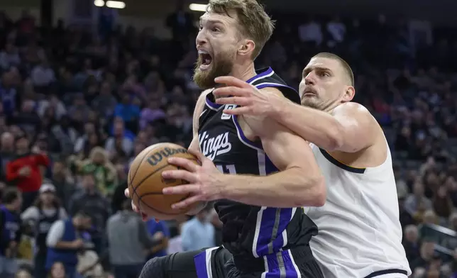 Sacramento Kings forward Domantas Sabonis, left, is guarded by Denver Nuggets center Nikola Jokic during the second half of an NBA basketball game in Sacramento, Calif., Monday, Dec. 16, 2024. The Nuggets won 130-129. (AP Photo/Randall Benton)