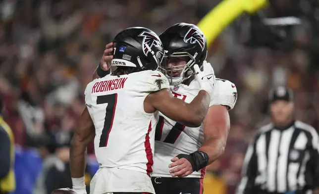 Atlanta Falcons running back Bijan Robinson (7) celebrates his touchdown with Arnold Ebiketie (17) during the first half of an NFL football game against the Washington Commanders, Sunday, Dec. 29, 2024, in Landover. (AP Photo/Stephanie Scarbrough)