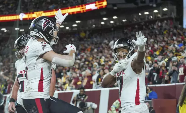 Atlanta Falcons running back Bijan Robinson (7) celebrates his touchdown with wide receiver Drake London during the first half of an NFL football game against the Washington Commanders, Sunday, Dec. 29, 2024, in Landover. (AP Photo/Stephanie Scarbrough)