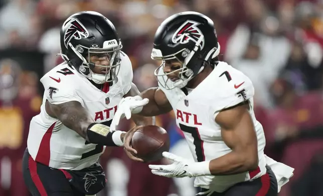 Atlanta Falcons quarterback Michael Penix Jr. (9) hands off to running back Bijan Robinson (7) during the first half of an NFL football game against the Washington Commanders, Sunday, Dec. 29, 2024, in Landover. (AP Photo/Stephanie Scarbrough)