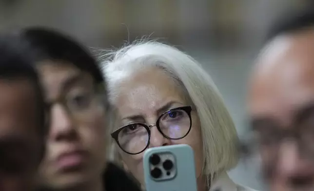 Mahnaz Tayarani, center, mother of Nima Momeni, who is charged with murder in Cash App founder Bob Lee's stabbing death, records video as defense attorney Saam Zangeneh speaks to reporters after exiting the courtroom at the Hall of Justice for Momeni's murder trial Tuesday, Dec. 3, 2024, in San Francisco. (AP Photo/Godofredo A. Vásquez)