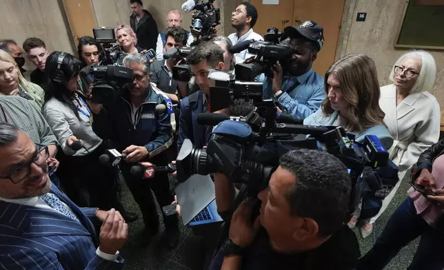 Mahnaz Tayarani, right, in white coat, mother of Nima Momeni, who is charged with murder in Cash App founder Bob Lee's stabbing death, watches as defense attorney Saam Zangeneh, bottom left, speaks to reporters after exiting the courtroom at the Hall of Justice for Momeni's murder trial Tuesday, Dec. 3, 2024, in San Francisco. (AP Photo/Godofredo A. Vásquez)