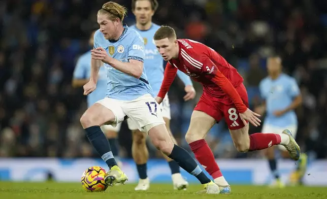 Manchester City's Kevin De Bruyne, left, and Nottingham Forest's Elliot Anderson challenge for the ball during the English Premier League soccer match between Manchester City and Nottingham Forest at the Etihad Stadium in Manchester, Wednesday, Dec. 4, 2024. (AP Photo/Dave Thompson)