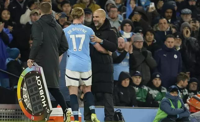 Manchester City's head coach Pep Guardiola, right, greets Kevin De Bruyne during a substitution at the English Premier League soccer match between Manchester City and Nottingham Forest at the Etihad Stadium in Manchester, Wednesday, Dec. 4, 2024. (AP Photo/Dave Thompson)